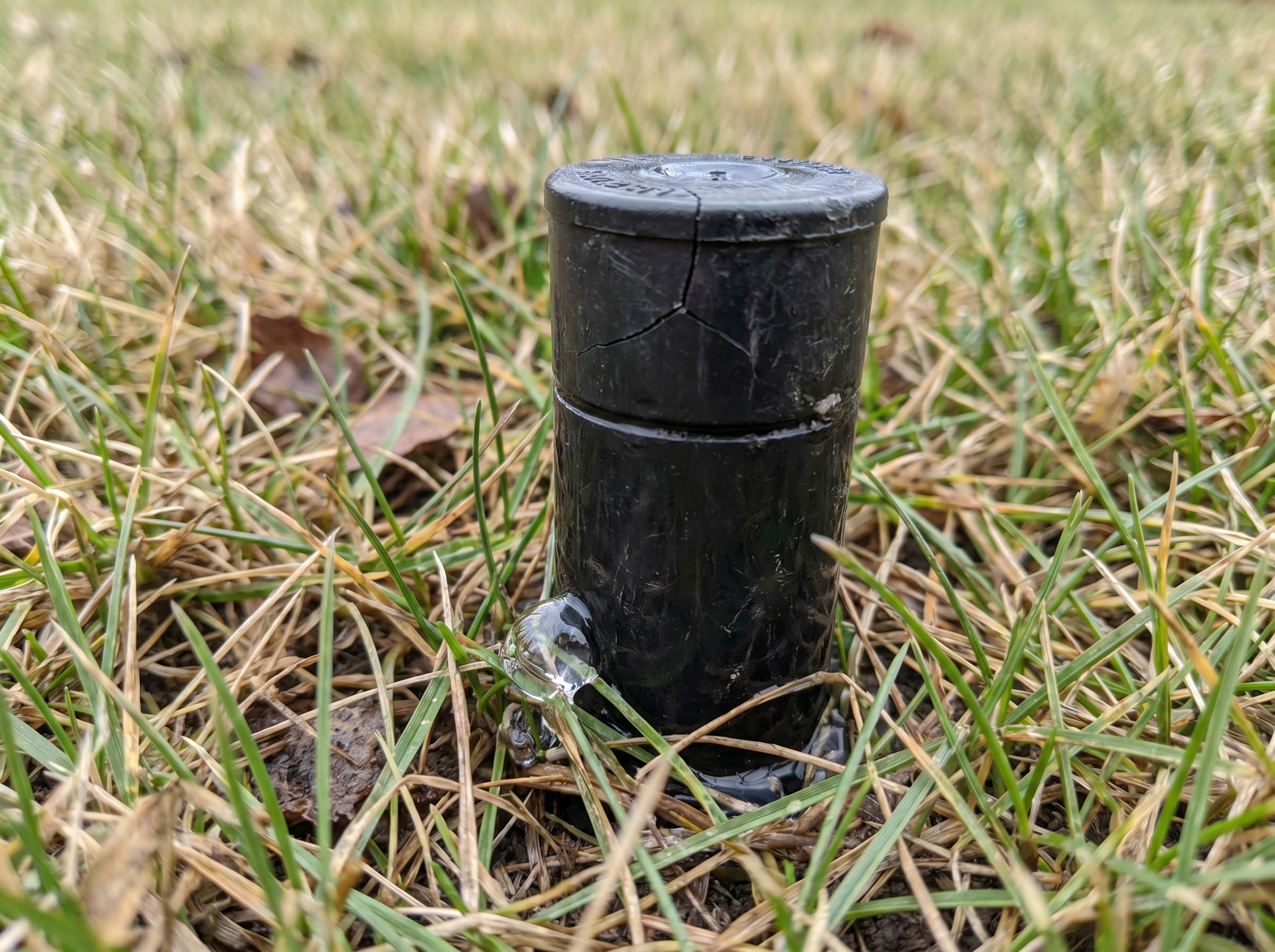 Close-up of a cracked sprinkler head leaking water from winter freeze damage